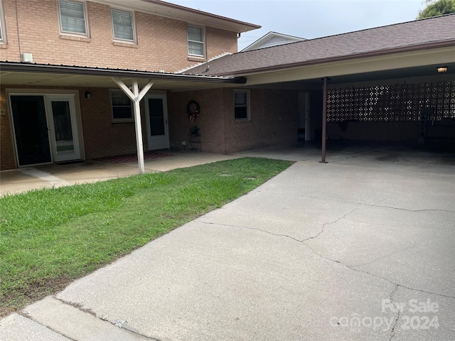 rear view of property with a carport and a lawn