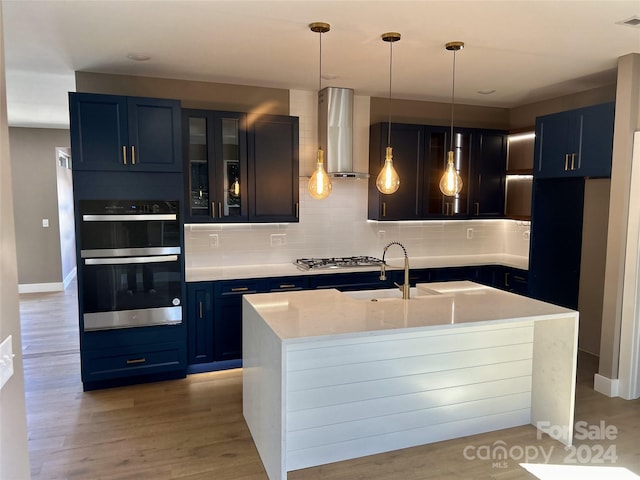 kitchen featuring blue cabinets, island exhaust hood, appliances with stainless steel finishes, and decorative backsplash