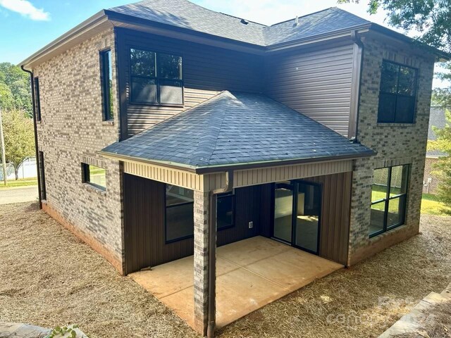 1243 10th Street Pl NW, Hickory, NC 28601 - view of home's exterior featuring a patio, a shingled roof, and brick siding