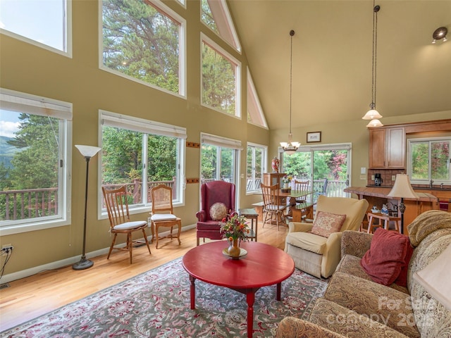 living room featuring an inviting chandelier, sink, a towering ceiling, and light hardwood / wood-style floors