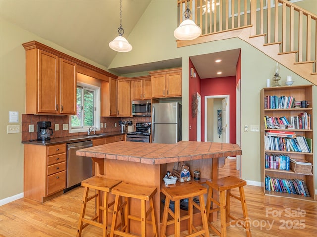 kitchen featuring decorative backsplash, light hardwood / wood-style flooring, stainless steel appliances, and a breakfast bar