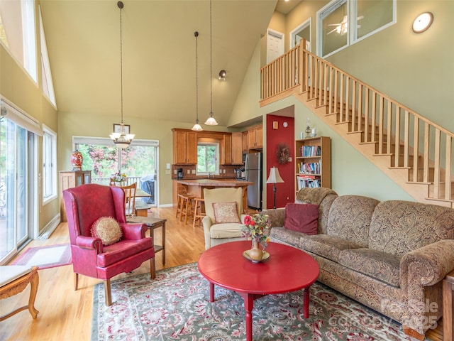 living room with an inviting chandelier, high vaulted ceiling, and light hardwood / wood-style flooring