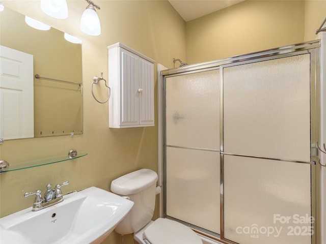 bathroom featuring an enclosed shower, sink, and toilet