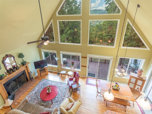 living room with a towering ceiling, ceiling fan, and light hardwood / wood-style flooring