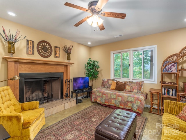 living room featuring ceiling fan and a tiled fireplace