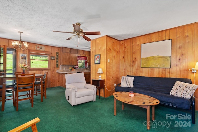 carpeted living room with ceiling fan with notable chandelier, wooden walls, and a textured ceiling