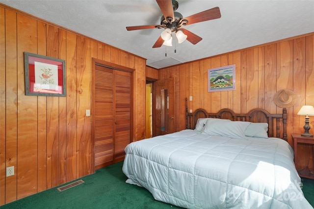 bedroom featuring wood walls, dark colored carpet, and ceiling fan