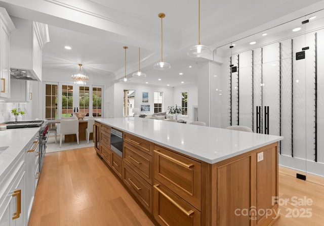 kitchen with white cabinetry, a center island, light stone countertops, and pendant lighting