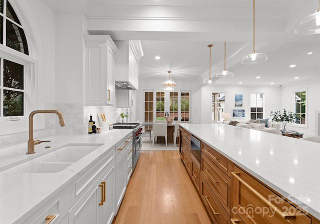 kitchen featuring pendant lighting, sink, white cabinetry, stainless steel appliances, and light stone countertops