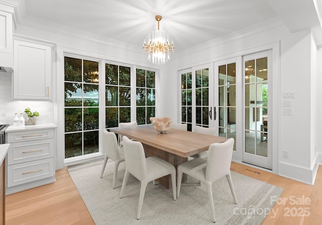 sunroom / solarium featuring french doors and a chandelier