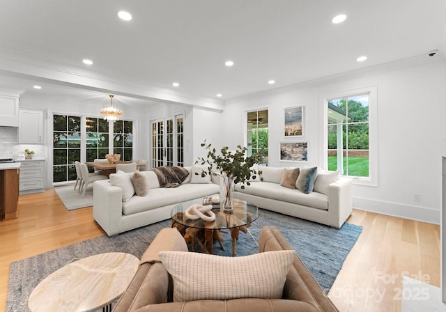 living room with ornamental molding, light hardwood / wood-style flooring, and a notable chandelier