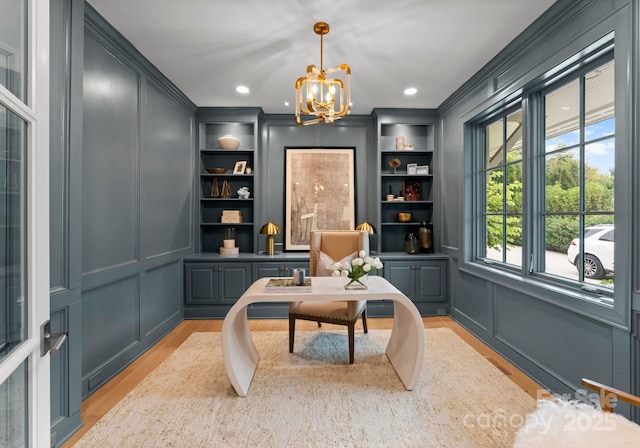 living area with a notable chandelier, crown molding, light hardwood / wood-style flooring, and built in features