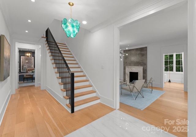 stairs with hardwood / wood-style flooring, a premium fireplace, and a chandelier