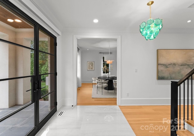 entrance foyer featuring ornamental molding, a chandelier, and hardwood / wood-style floors