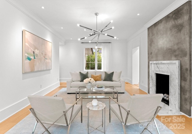 living room featuring crown molding, a fireplace, light hardwood / wood-style flooring, and a notable chandelier