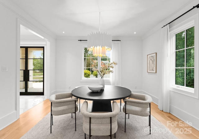 dining room featuring ornamental molding, a wealth of natural light, and light wood-type flooring