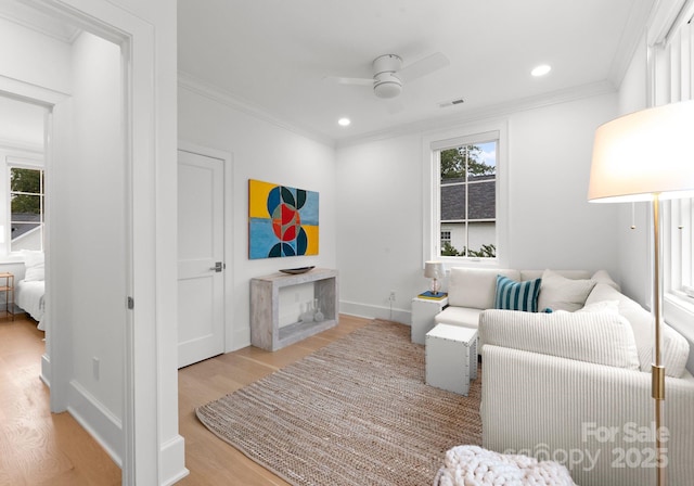 living room with crown molding, a healthy amount of sunlight, and light hardwood / wood-style floors