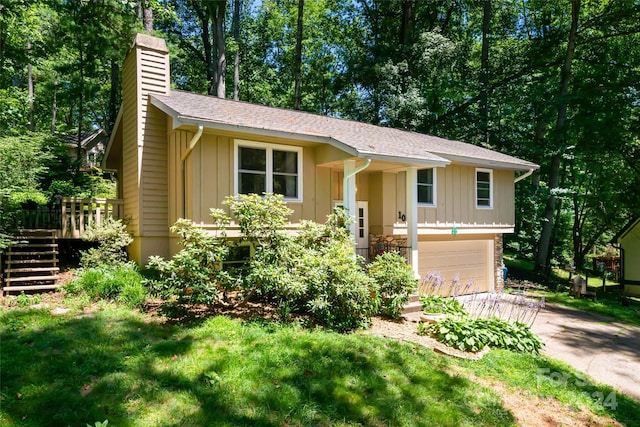 bi-level home featuring board and batten siding, a chimney, stairway, and an attached garage
