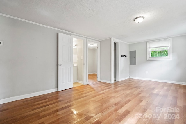 interior space featuring a textured ceiling, crown molding, light hardwood / wood-style floors, and electric panel