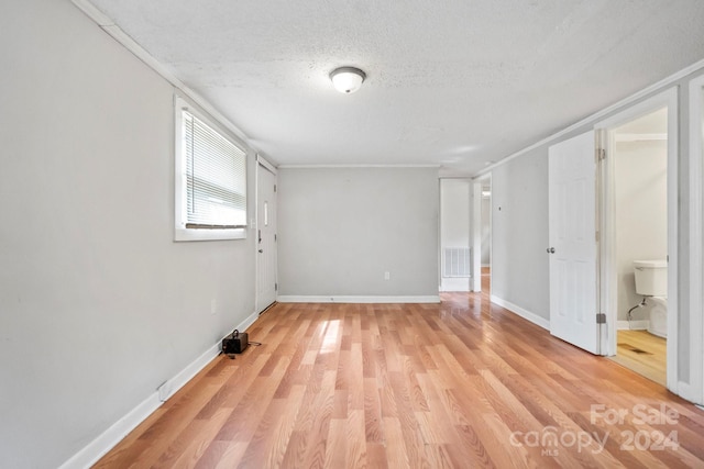 unfurnished bedroom featuring light hardwood / wood-style flooring, ensuite bath, and a textured ceiling