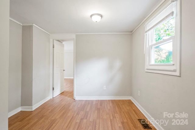 unfurnished room with light hardwood / wood-style flooring and crown molding