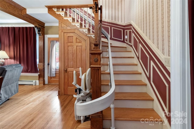 staircase with hardwood / wood-style floors, ornamental molding, and a baseboard heating unit