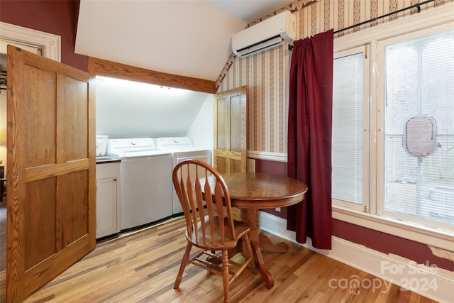 dining room featuring washing machine and clothes dryer, an AC wall unit, light hardwood / wood-style flooring, and vaulted ceiling