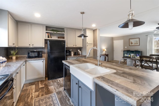 kitchen with black appliances, tasteful backsplash, dark hardwood / wood-style flooring, pendant lighting, and a kitchen island with sink