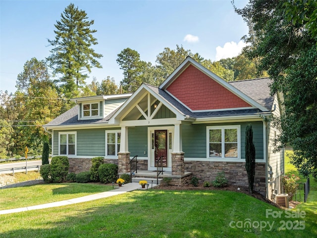 craftsman-style house featuring a porch, stone siding, a shingled roof, and a front lawn