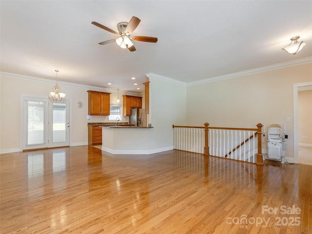 unfurnished living room with baseboards, ornamental molding, a sink, and light wood-style floors