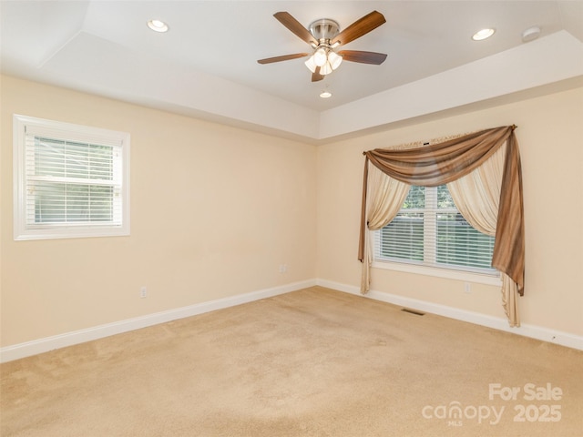 empty room featuring baseboards, a raised ceiling, light colored carpet, ceiling fan, and recessed lighting