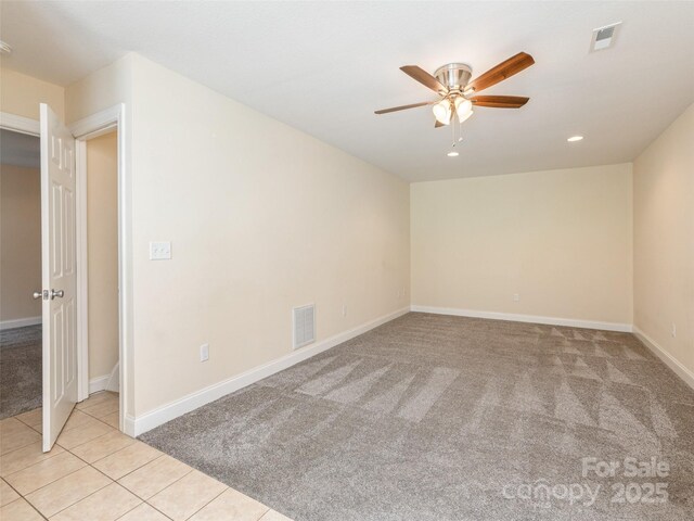 unfurnished room with light colored carpet, visible vents, ceiling fan, and light tile patterned floors