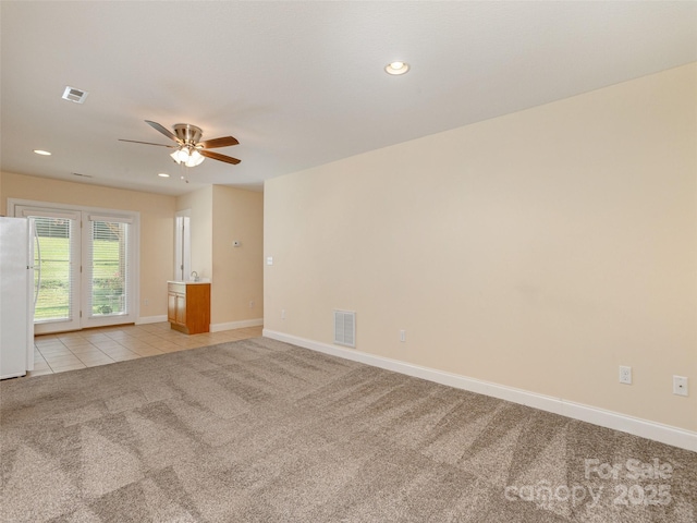 empty room with light carpet, baseboards, visible vents, and light tile patterned flooring