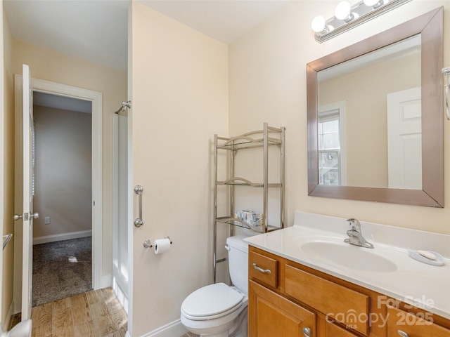 bathroom featuring wood finished floors, vanity, toilet, and baseboards