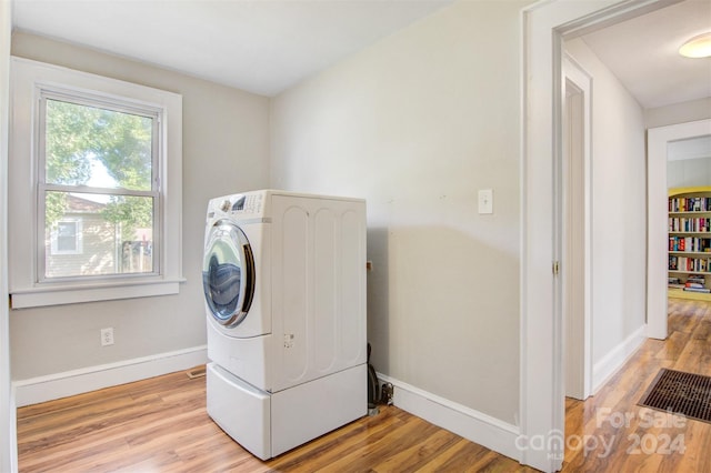 clothes washing area with light hardwood / wood-style floors and washer / dryer