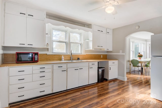 kitchen with dark wood-type flooring, white fridge, white cabinetry, and a wealth of natural light