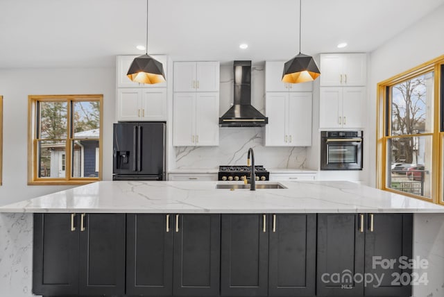 kitchen with a large island with sink, white cabinetry, wall chimney exhaust hood, and appliances with stainless steel finishes