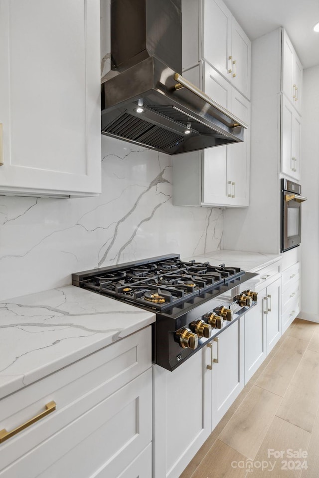 kitchen with stainless steel oven, gas cooktop, tasteful backsplash, range hood, and white cabinets