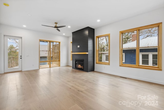 unfurnished living room featuring a large fireplace, light hardwood / wood-style floors, and plenty of natural light