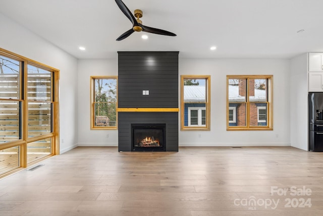 unfurnished living room featuring ceiling fan, a fireplace, and light hardwood / wood-style floors