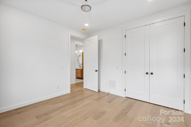 unfurnished bedroom with light wood-type flooring and a closet