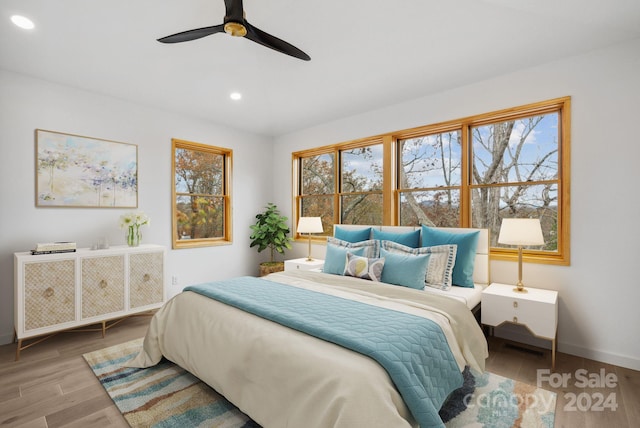 bedroom with ceiling fan, light hardwood / wood-style floors, and multiple windows