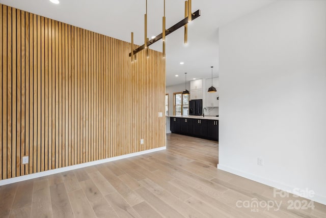 unfurnished living room with wooden walls and light hardwood / wood-style flooring