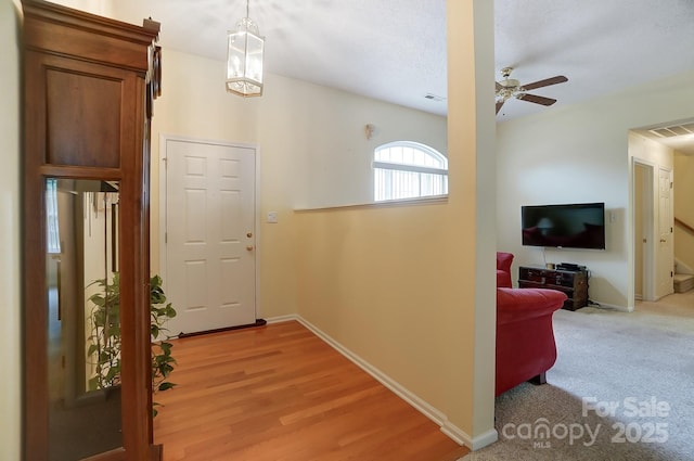 foyer with light wood-type flooring, baseboards, visible vents, and ceiling fan