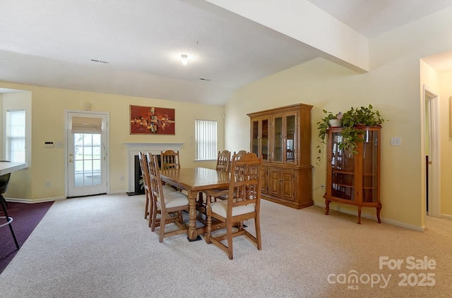 dining space with vaulted ceiling, baseboards, visible vents, and light colored carpet