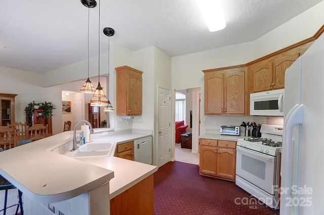 kitchen featuring a peninsula, white appliances, a sink, light countertops, and a kitchen bar