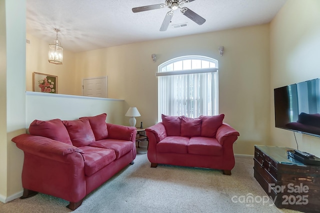 living area with carpet, visible vents, a textured ceiling, and ceiling fan with notable chandelier