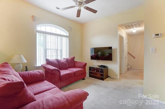 living area featuring carpet floors, visible vents, baseboards, stairs, and a ceiling fan