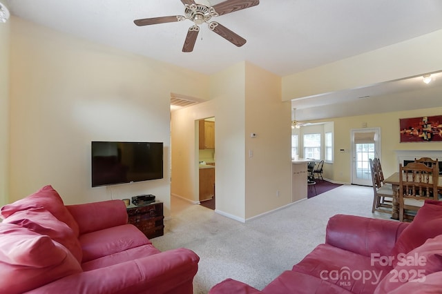 living room featuring carpet floors, ceiling fan, visible vents, and baseboards