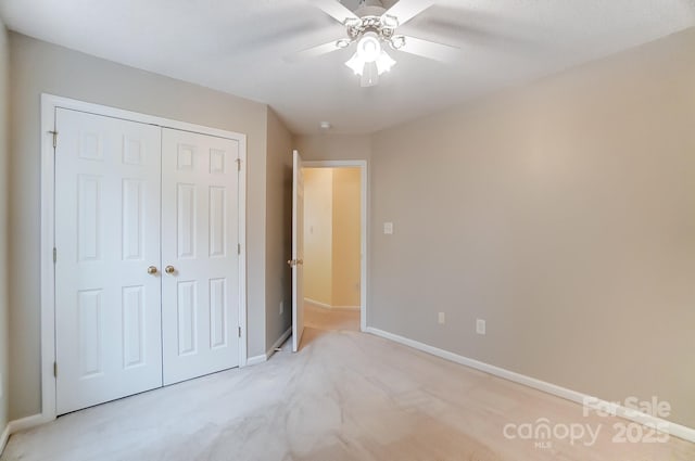 unfurnished bedroom featuring a closet, light carpet, ceiling fan, and baseboards